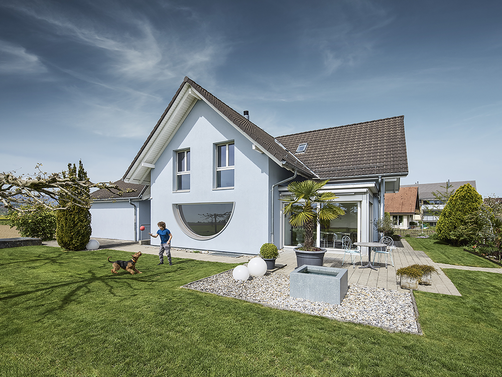Lachendes Haus mit Kind und Hund im Garten.