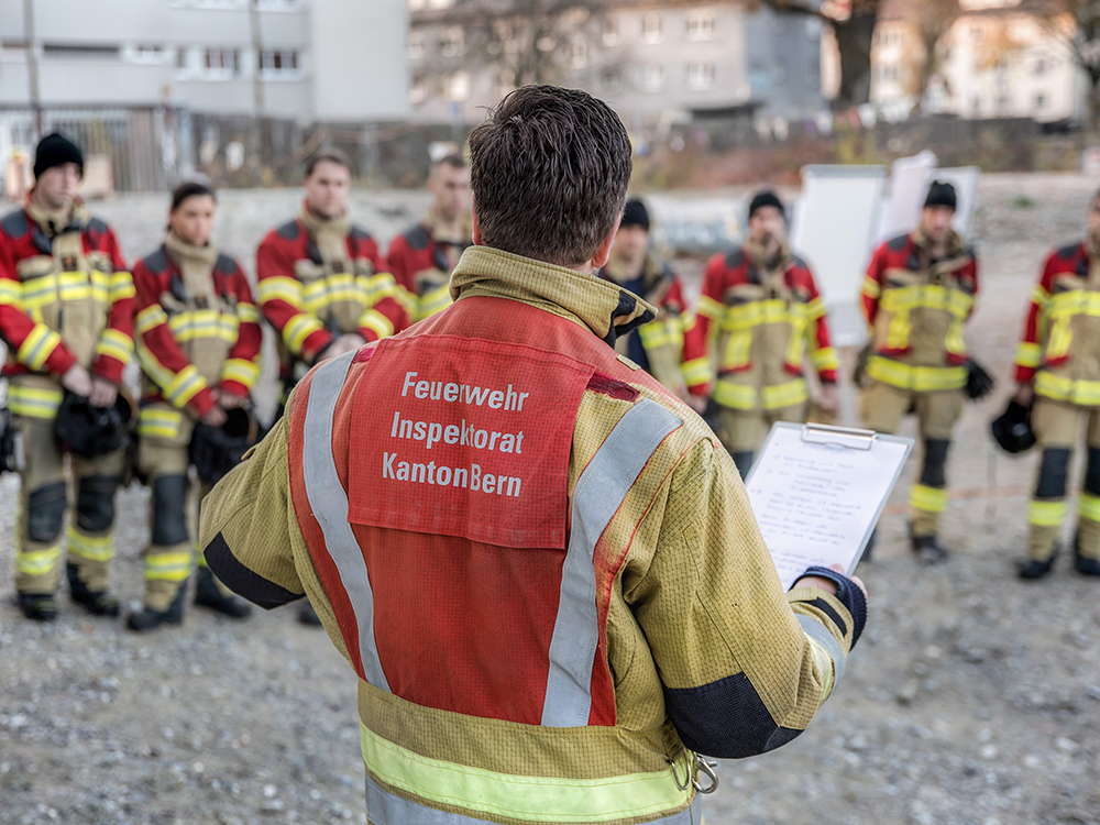 Feuerwehrmann steht mit einem Block vor Feuerwehrleuten.