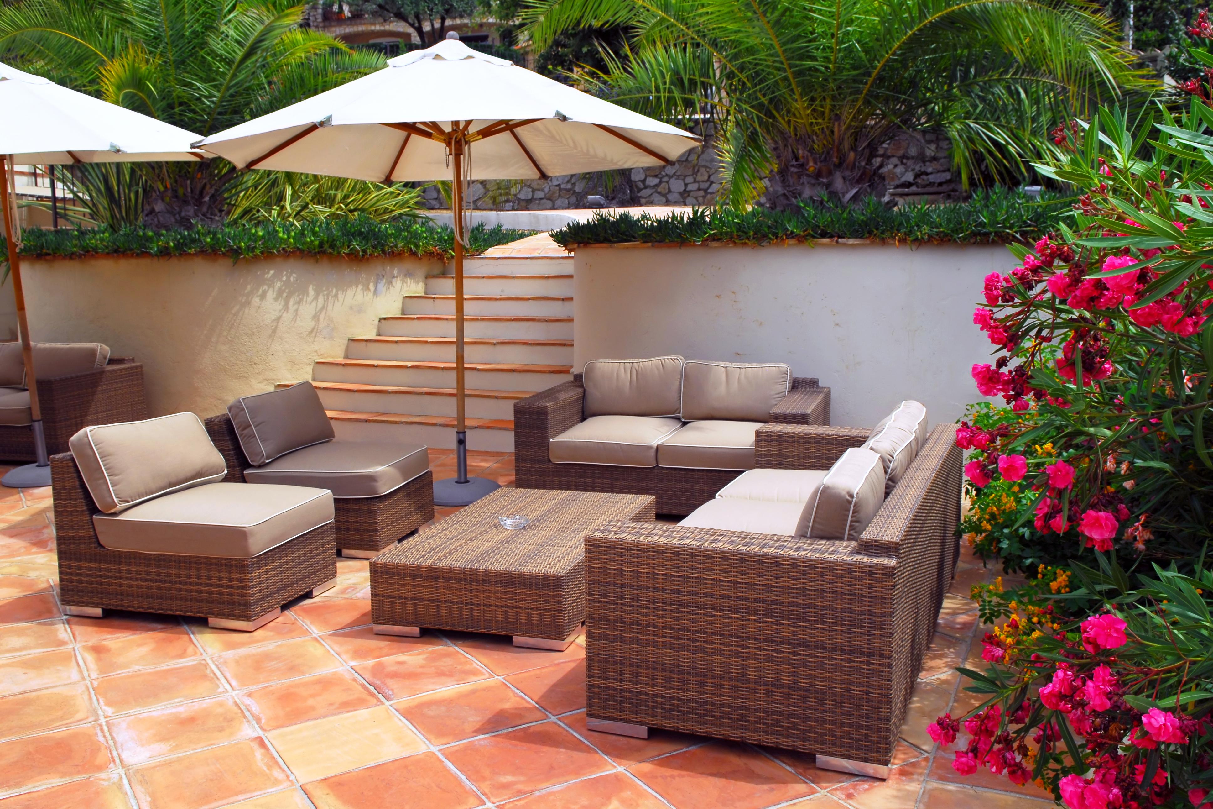 Une terrasse avec un sol en terre cuite brune et un salon.