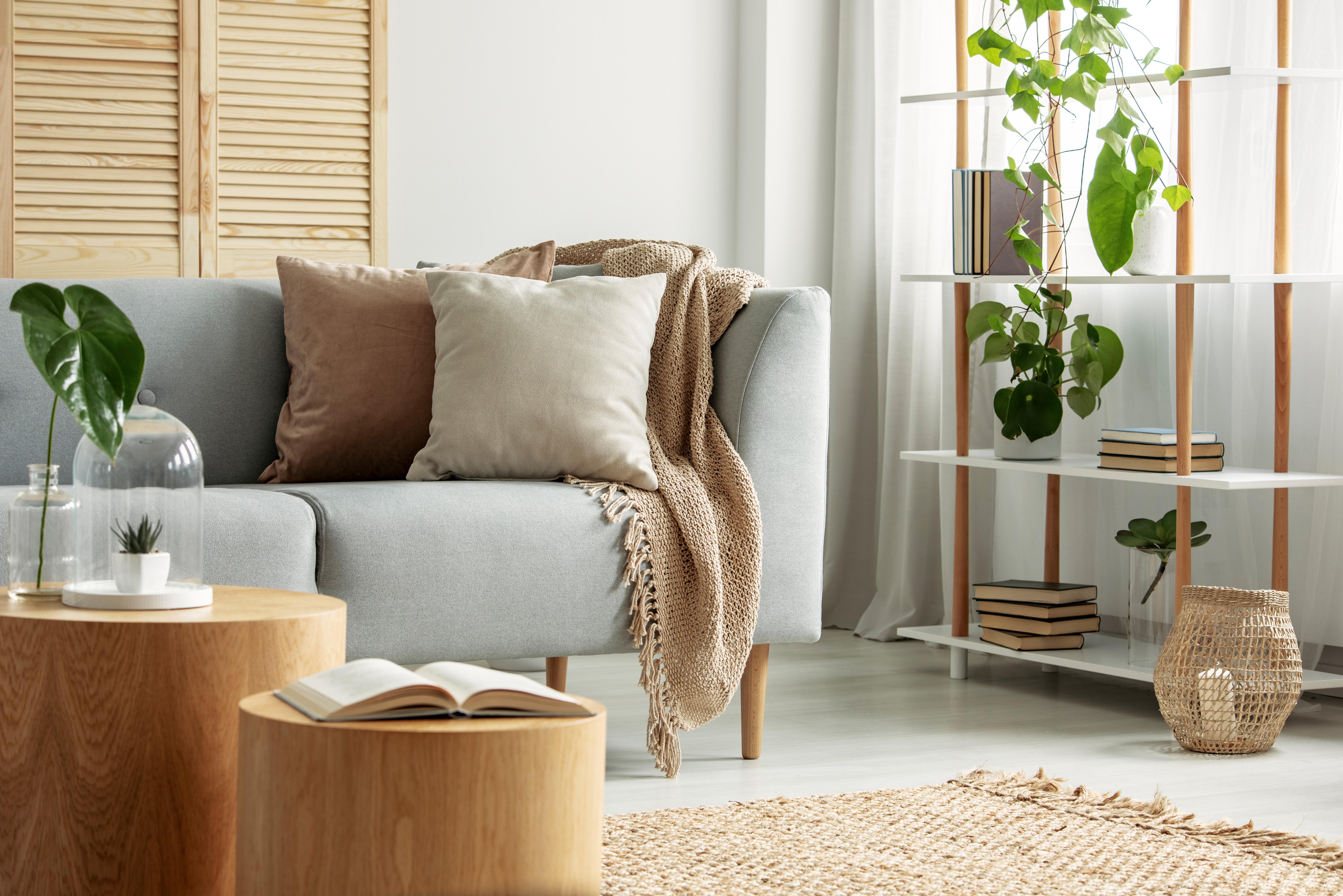 Ein Wohnzimmer mit einem grauen Sofa und natürlichen Accessoires aus Leinen und Holz.