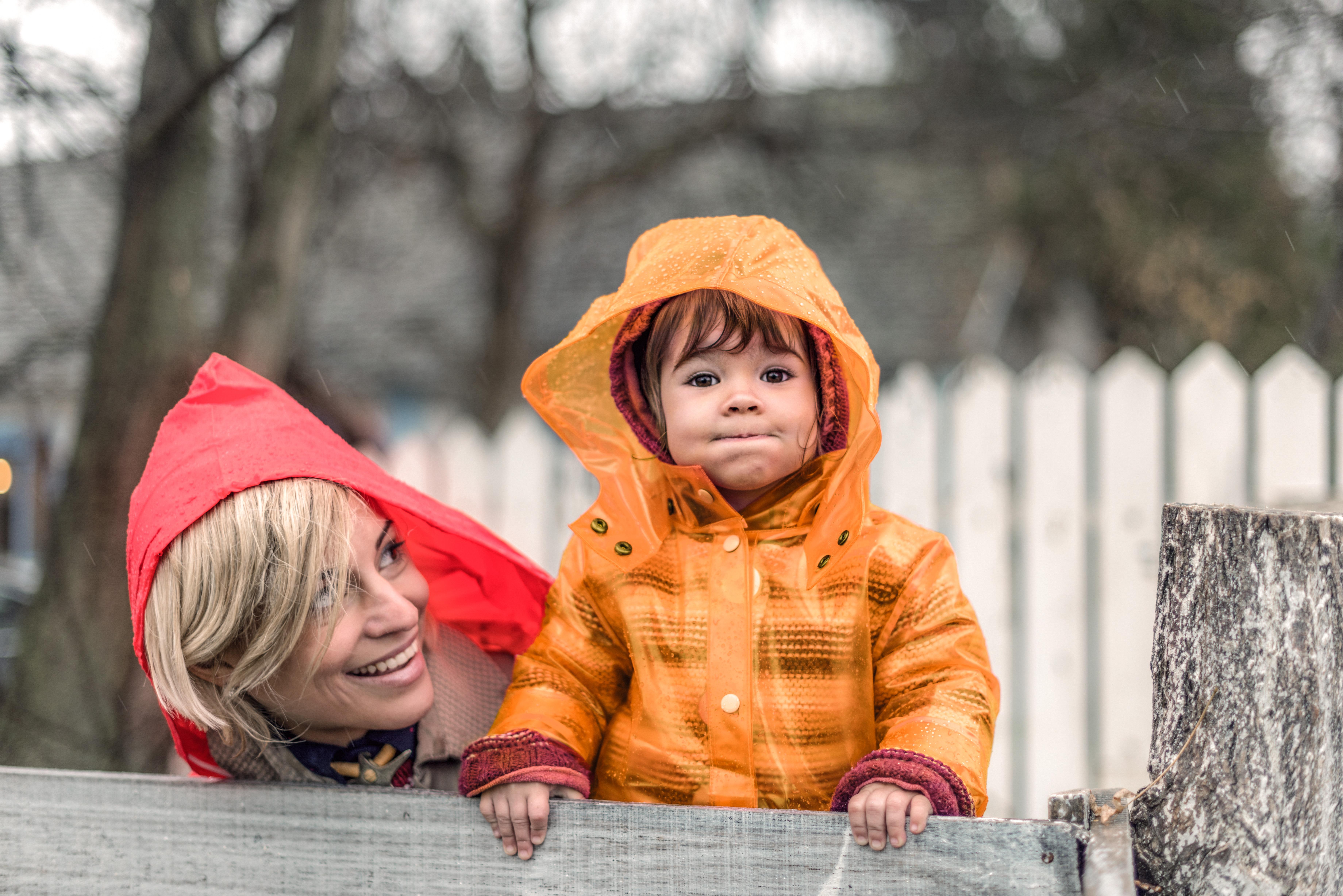  Mutter und Kind lachen und tragen Regenjacken